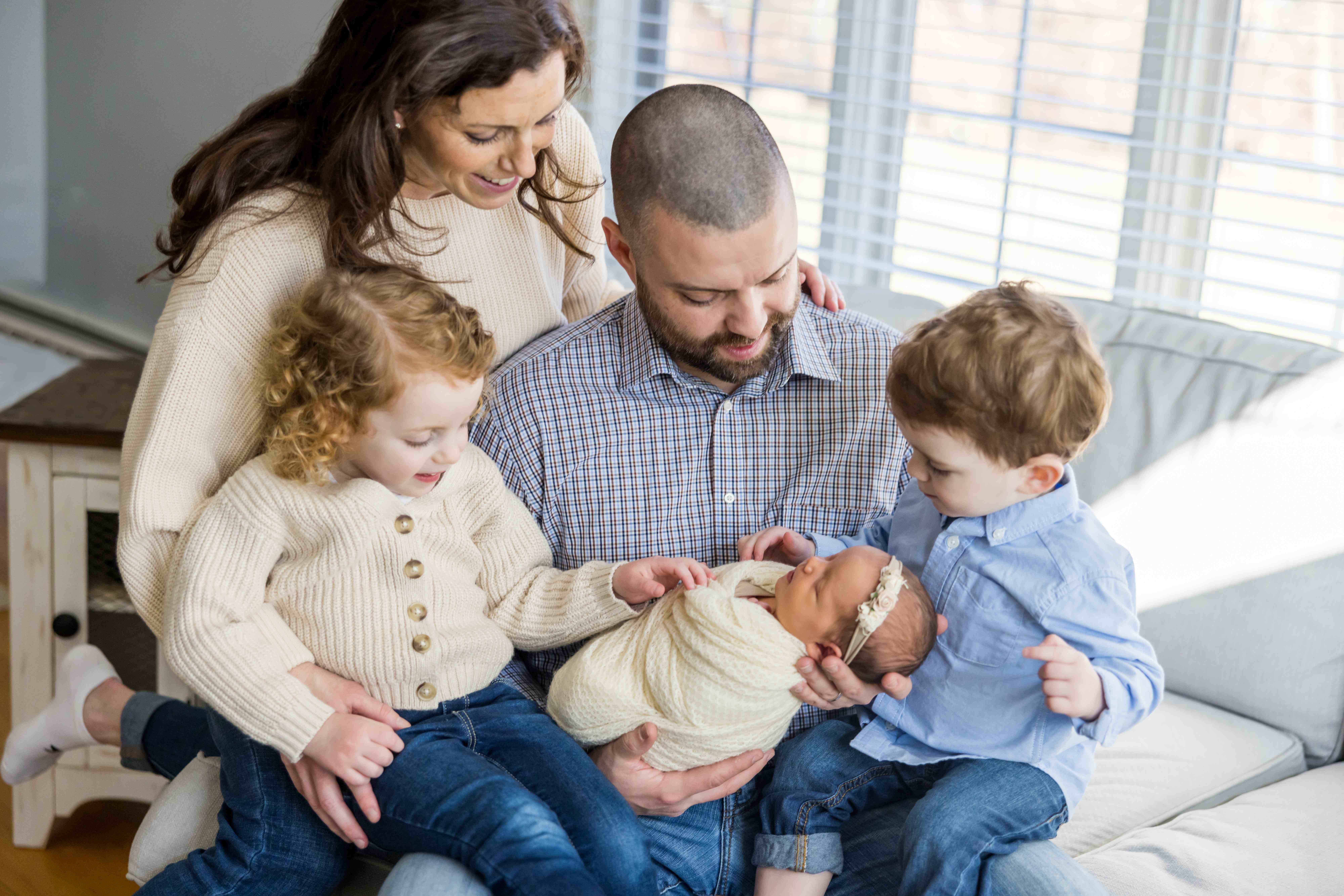 Family with two young children and a swaddled newborn